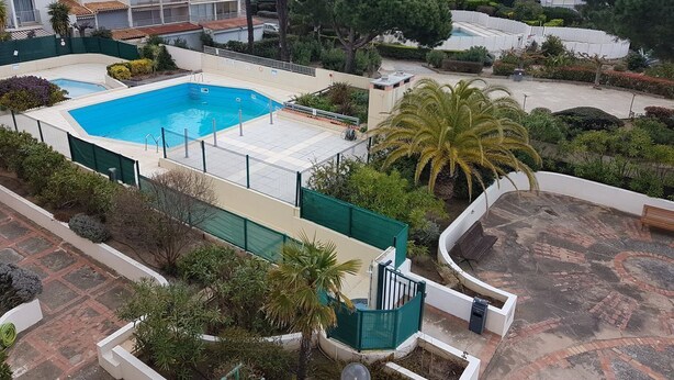 Ein Luftbild eines Wohnkomplexes mit Schwimmbad, umgeben von Grünflächen und angrenzenden Gebäuden.