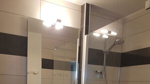 Ein Badezimmer mit einem weißen Waschbecken, einem Spiegel und einer Dusche.