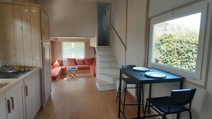 Angolo cottura compatto con zona pranzo, pavimento in legno e vista dalla finestra.