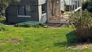 Una casa moderna con un'estensione in vetro, un patio con mobili da esterno e vista sull'acqua.