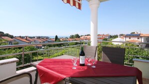 A balcony with a red tablecloth, a bottle of wine, and glasses, overlooking a residential area with red-roofed houses. - With sea view in Apartment Bernstein in Porec. (Porec)