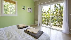 A bedroom with a large window, a bed with two blankets, and a wall-mounted air conditioner. - House w/ pool - 12 pers., quiet garden w/ stunning view on the BASQUE COUNTRY (ARCANGUES)