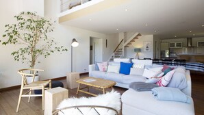 A spacious living room with a high ceiling, a staircase, and a kitchen in the background. - House w/ pool - 12 pers., quiet garden w/ stunning view on the BASQUE COUNTRY (ARCANGUES)