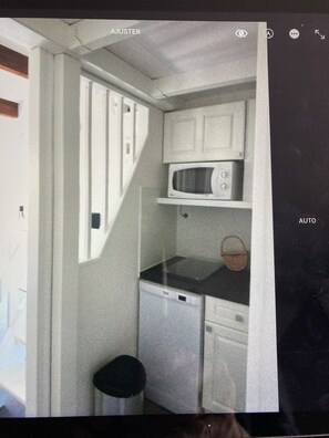 Uma cozinha compacta com micro-ondas, pia e uma pequena lixeira.