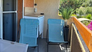 A balcony with two chairs, a table, and a small kitchen area with a sink and countertop. - T2 Mezzanine in Ste Maxime Gulf of St Tropez (Sainte-Maxime)