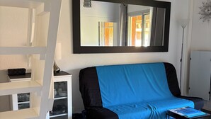A room with a sofa, a small table, a ladder, a shelf unit, and a large mirror. - T2 Mezzanine in Ste Maxime Gulf of St Tropez (Sainte-Maxime)