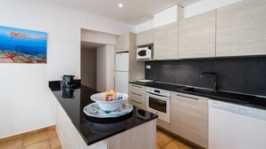 A modern kitchen with a black countertop, wooden cabinets, a microwave, oven, and dishwasher. - CASA TURCHINA - VILLA **** - Heated swimming pool - Near L'Ile-Rousse beach (MONTICELLO)