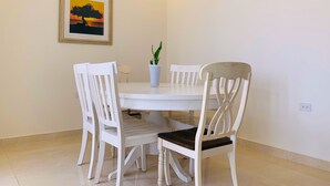 A dining area with a round table, four white chairs, a potted plant, and a framed picture on the wall. - Romantic, Beautiful Sunsets w/Private Pool (West Punt)