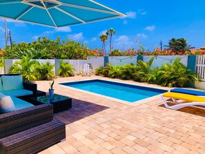 A swimming pool with a tiled edge, surrounded by a patio area with wicker furniture and a white fence. - Romantic, Beautiful Sunsets w/Private Pool (West Punt)