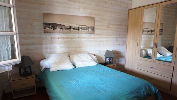 A bedroom with a bed, nightstands, a wardrobe, and a wall-mounted artwork. - Villa familiale avec chalet proche centre et plage (044) (Biscarrosse)