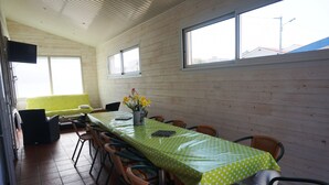 A dining area with a long table covered in a green polka dot tablecloth, surrounded by wicker chairs. - Villa familiale avec chalet proche centre et plage (044) (Biscarrosse)