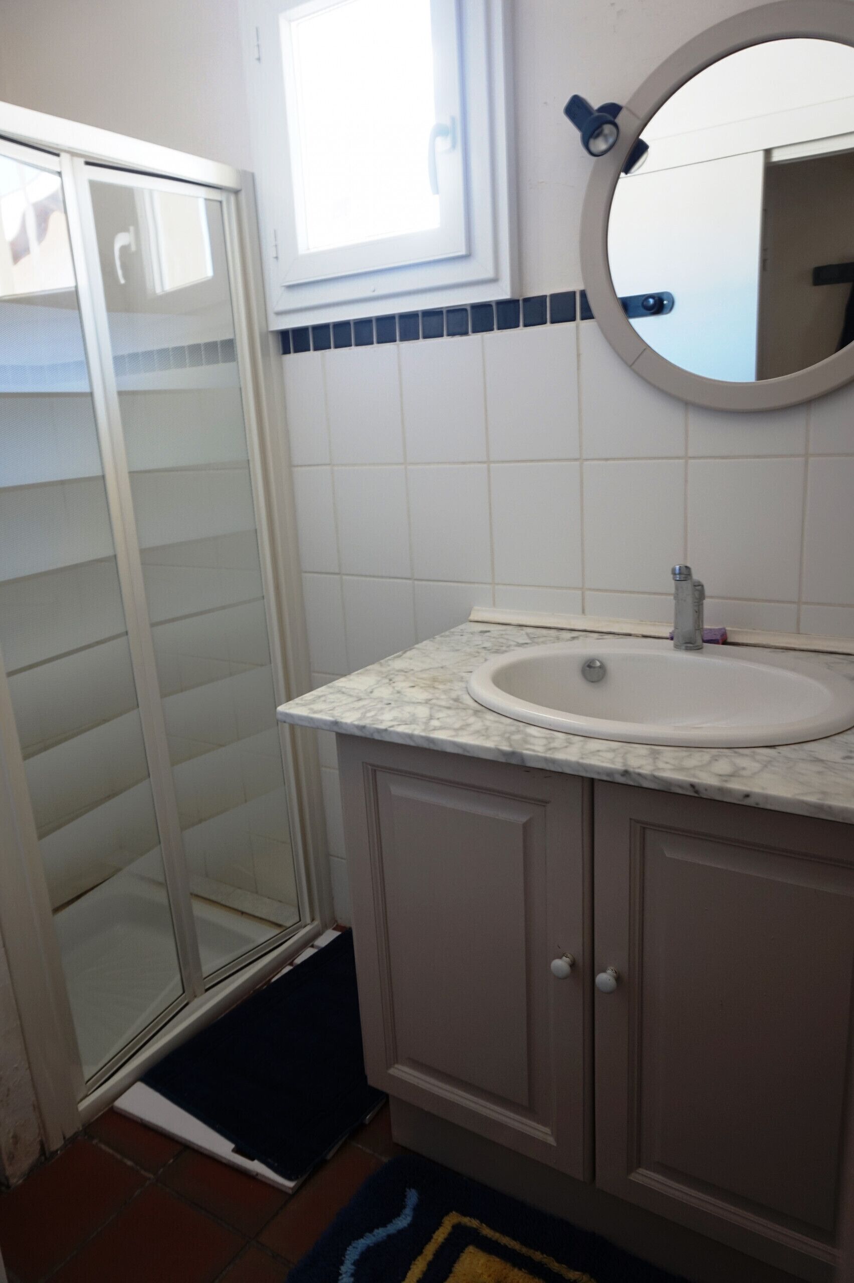 Een badkamer met een witte wastafel, een spiegel en een douchedeur.