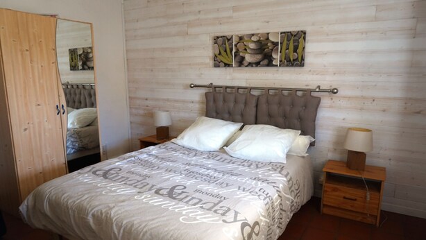 A bedroom with a bed, nightstands, a mirror, and a wooden headboard. - Villa familiale avec chalet proche centre et plage (044) (Biscarrosse)