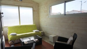 A cozy room with a green sofa, a small table, and two chairs. - Villa familiale avec chalet proche centre et plage (044) (Biscarrosse)