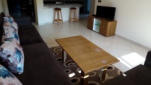 A living room with a sofa, a coffee table, and a TV stand. - Atlantic Ocean Residence 1501 (Asilah)