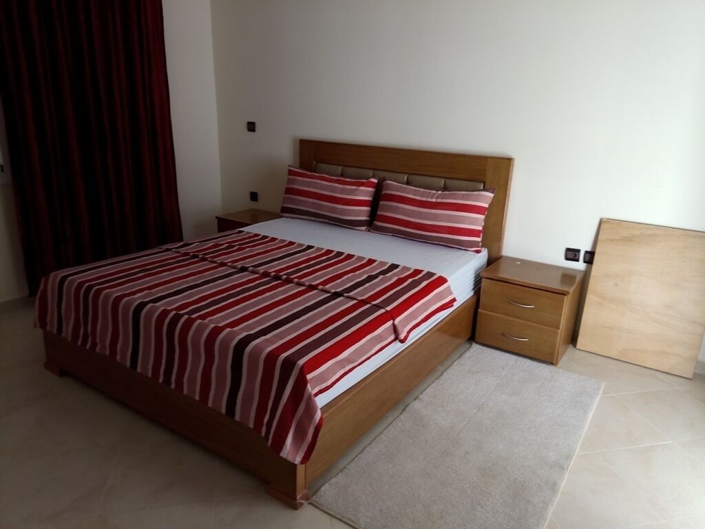 A bedroom with a wooden bed, striped bedding, a nightstand, and a wooden headboard.