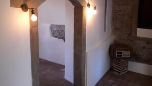 A rustic interior with stone arches, a stone wall, and a tiled floor. - B&B Le Vie del Borgo (Castiglione di Sicilia)