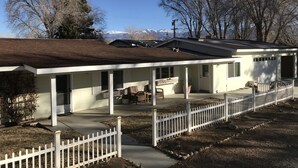A single-story house with a covered porch, a fenced yard, and a mountain backdrop. - Beautiful  Spacious Suite w/private entrance (Bishop)