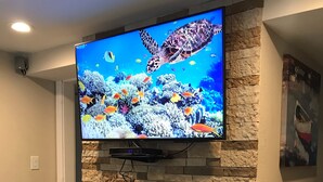 A flat-screen TV mounted on a stone wall above a fireplace.
