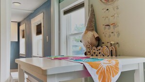 A room with a white table, a white bench, and a wall decoration with shells and a starfish.