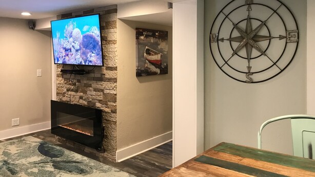 A living room with a stone fireplace, a flat-screen TV, and a wall-mounted compass.