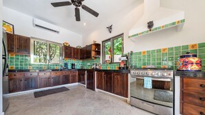 A kitchen with dark wooden cabinets, a large stove, and green-tiled backsplash.
