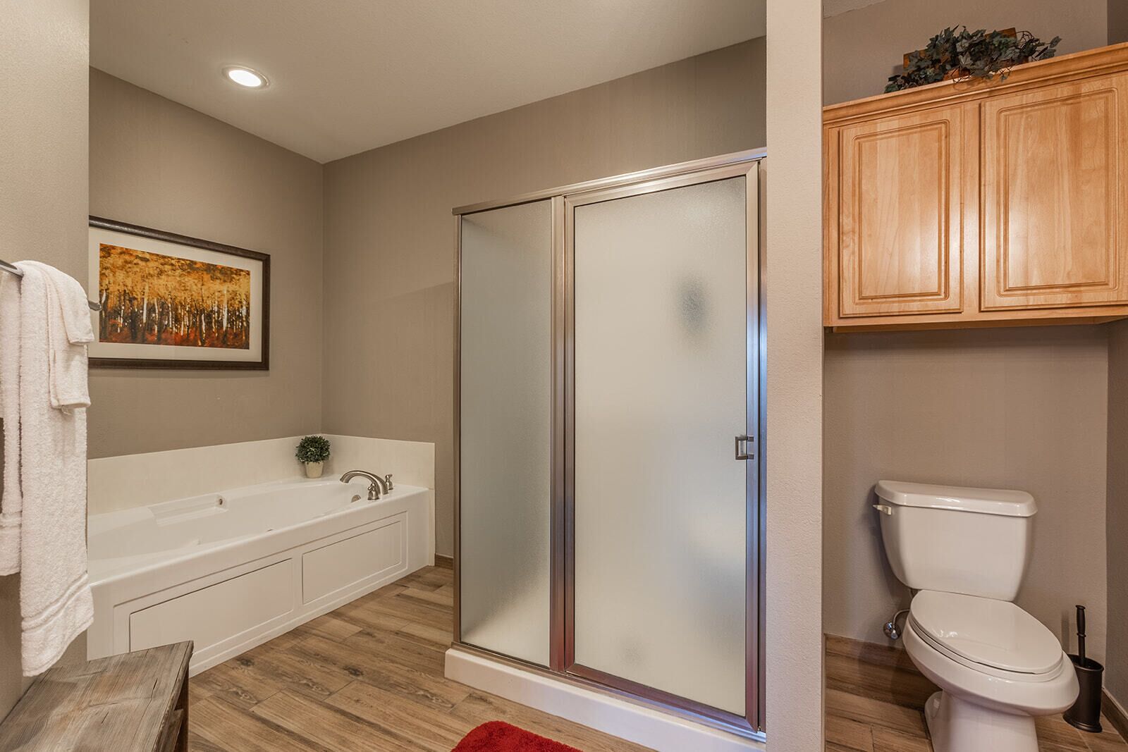 A bathroom with a glass-enclosed shower, a white bathtub, and a toilet.
