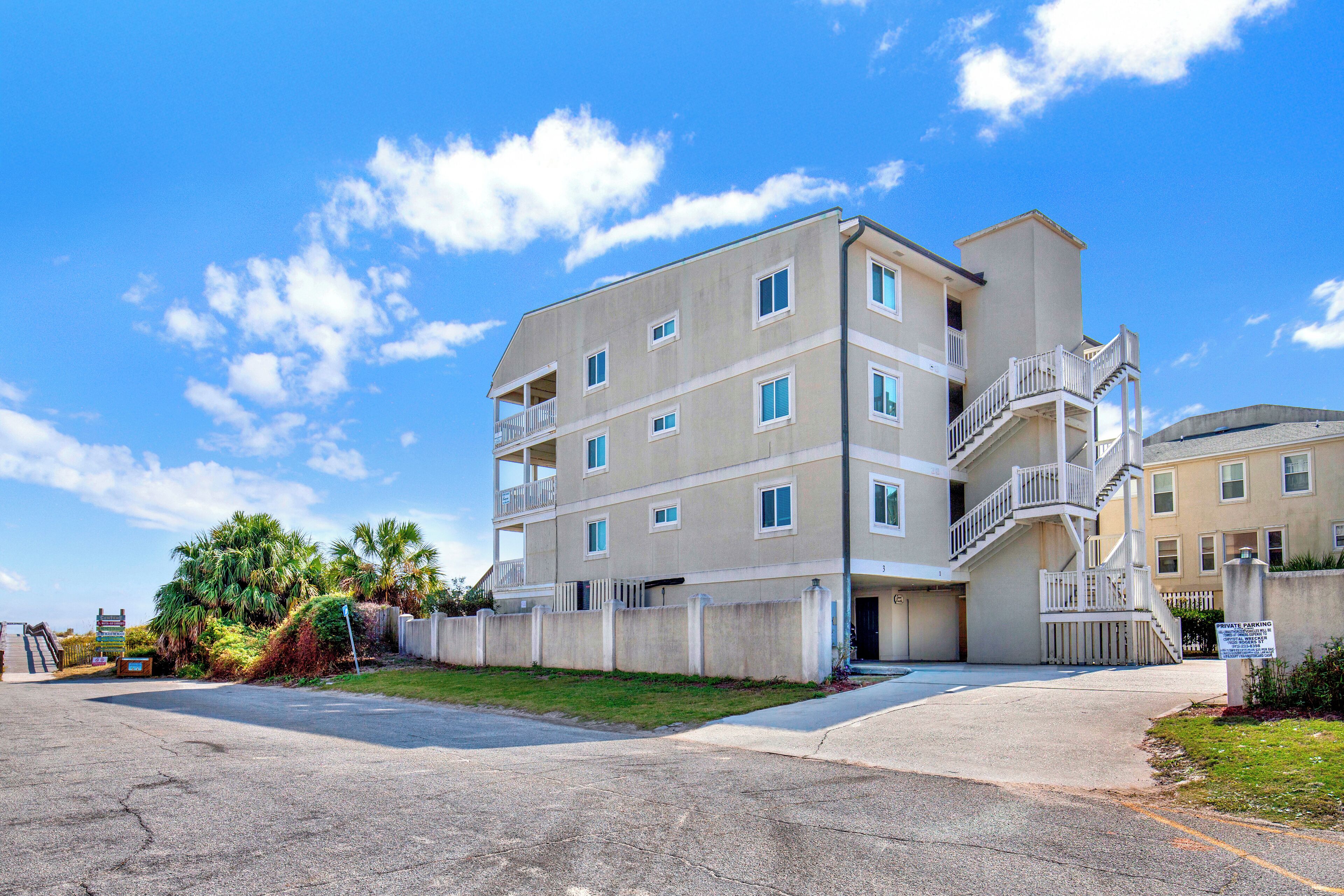 A multi-story residential building with balconies, a central staircase, and a gated entrance.