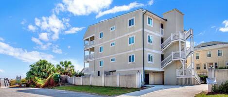 A multi-story residential building with balconies, a central staircase, and a gated entrance.