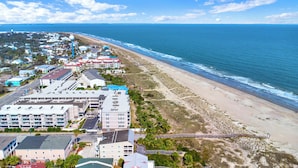 An aerial view of a coastal area with a beach, ocean, and a hotel complex with multiple buildings and a parking lot. - Mid beach ocean front 3 bedroom 2 bath condo (Tybee Island)