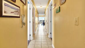 A hotel hallway with framed pictures on the walls, a welcome sign, and a sign indicating a beach view. - Mid beach ocean front 3 bedroom 2 bath condo (Tybee Island)