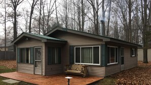 A small, single-story cabin with a porch, a bench, and a small table. - Walk to Lake cottage with beautiful Higgins Lk "Gold Coast" access (Roscommon)
