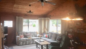 A cozy living room with a wooden ceiling, a sofa set, a coffee table, and a ceiling fan. - Walk to Lake cottage with beautiful Higgins Lk "Gold Coast" access (Roscommon)