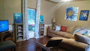 Een woonkamer met een bank, een televisie en een boekenkast.