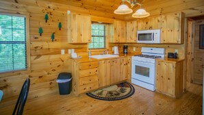Cocina de cabaña de madera con una isla central, estufa blanca y un microondas sobre la encimera.