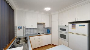A modern kitchen with white cabinets, a built-in stove, a double oven, and a refrigerator.