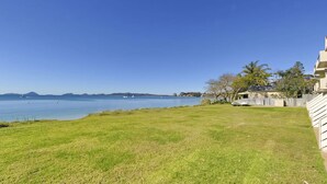 A grassy area with a view of a calm body of water and distant landforms.