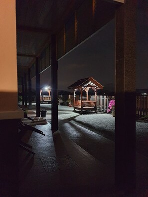 A covered outdoor area with a wooden gazebo, benches, and potted plants.