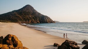 Une plage avec un promontoire rocheux et une montagne en arrière-plan.
