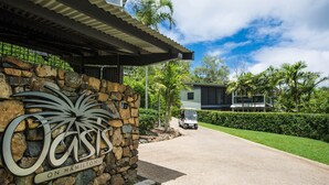 A stone wall with a sign reading "Crisis on Hamilton" and a modern house in the background. - Oasis 2, Beautiful Apartment on Hamilton Island (Whitsundays)