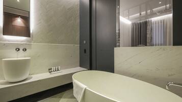 A modern bathroom with a large white sink, a bathtub, and a mirror above the sink.