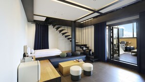 Une chambre d’hôtel moderne équipée d’un lit, d’un coin salon et d’un escalier.