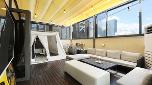 Une terrasse sur le toit, dotée d’un auvent blanc, d’un canapé, d’une table basse et d’un ventilateur.