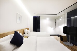 A modern hotel room with a large bed, a bedside table, a TV, and a shower area.