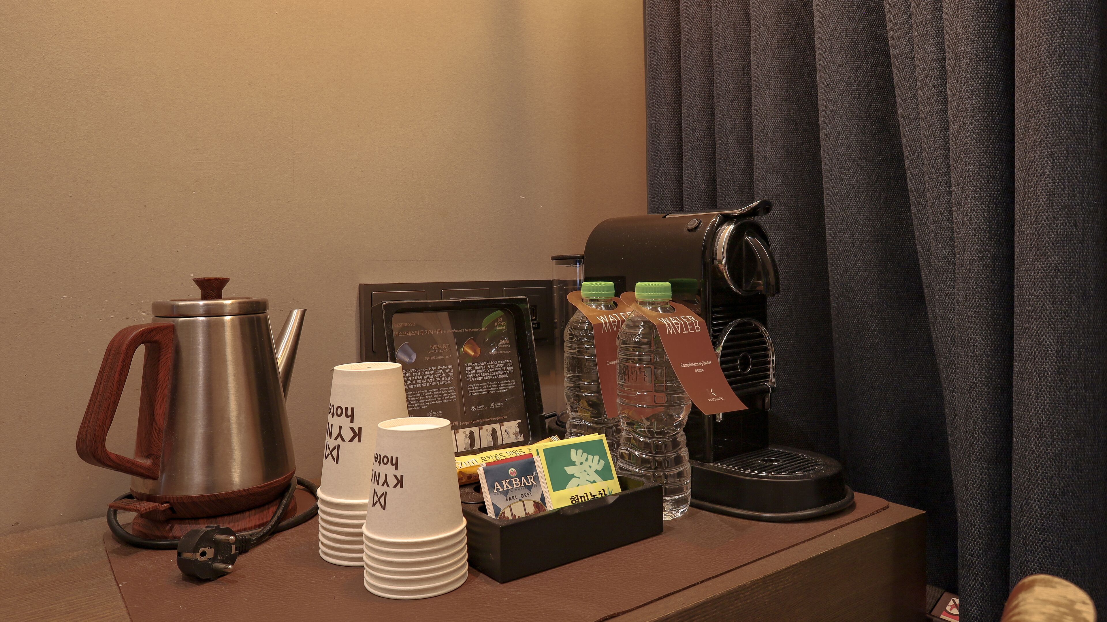 A coffee station with a coffee pot, cups, a coffee machine, and bottled water.