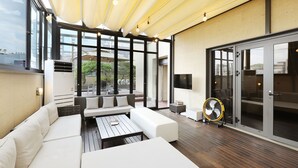 Un espace de vie extérieur moderne, avec un ensemble de canapés blancs, une petite table et un ventilateur.