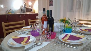 A dining table set with plates, cutlery, and glasses, with a kitchen in the background. - TMC Skopje Apartment (Skopje)