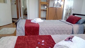 A hotel room with two beds, each with a red and white blanket, and a wooden wardrobe with lights. - TMC Skopje Apartment (Skopje)