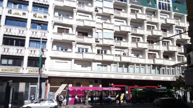 A multi-story building with balconies and a ground-level shop. - TMC Skopje Apartment (Skopje)