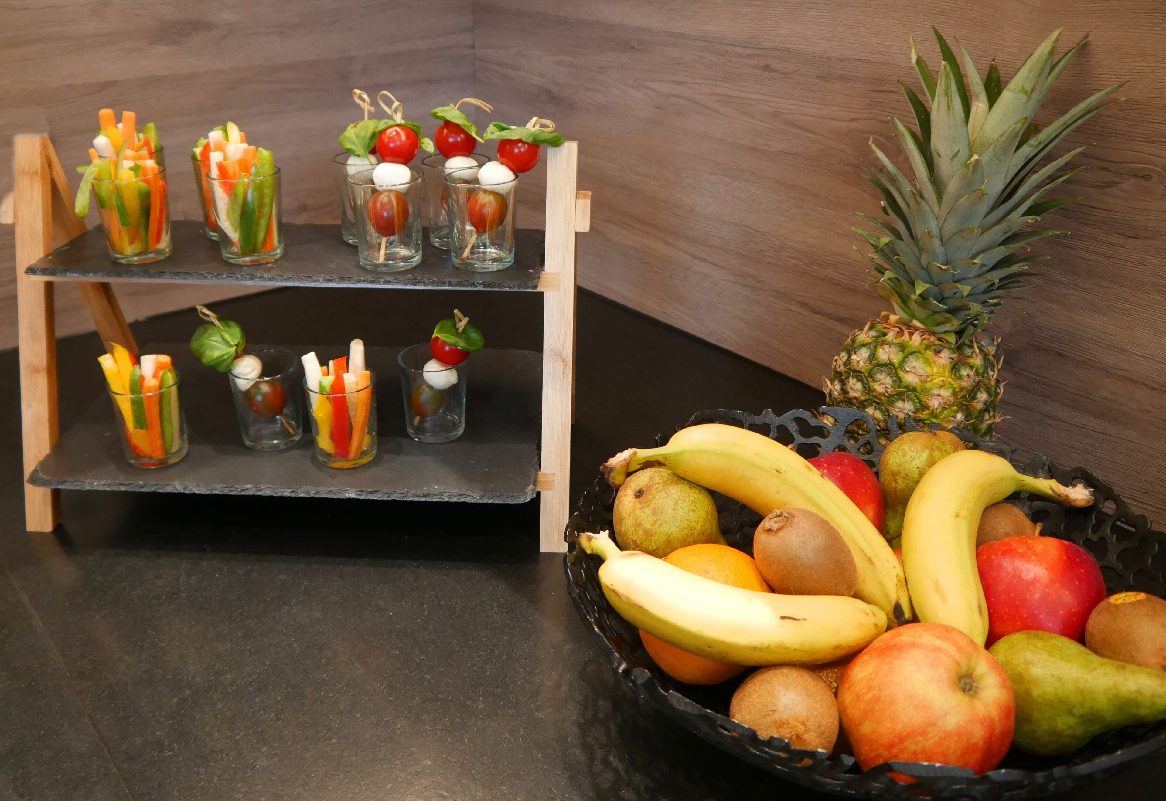 Una exhibición de frutas con una variedad de opciones como plátanos, manzanas y naranjas sobre una mesa.
